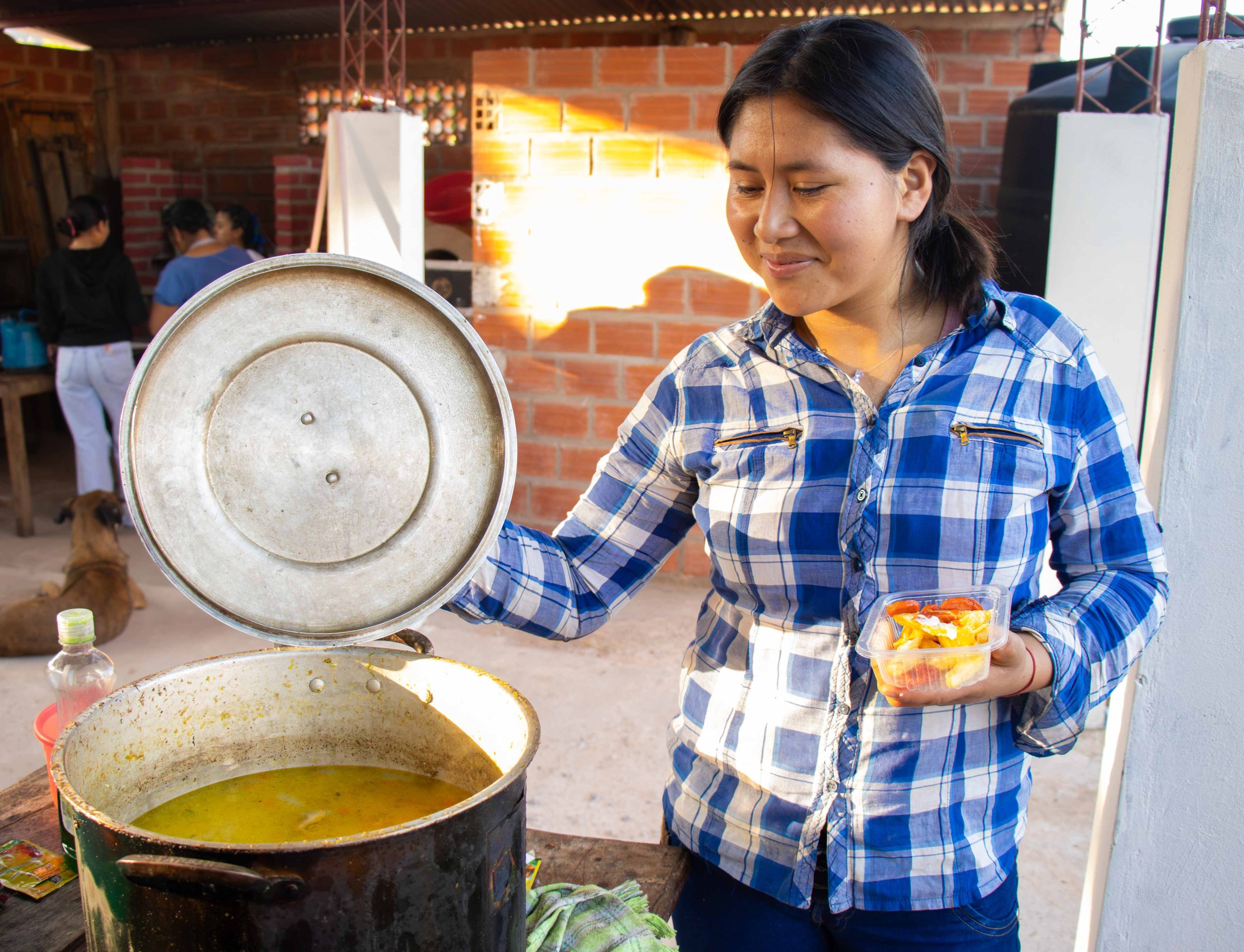 mujer joven guaraní mostrando sopa de maní tradicional del chaco en olla